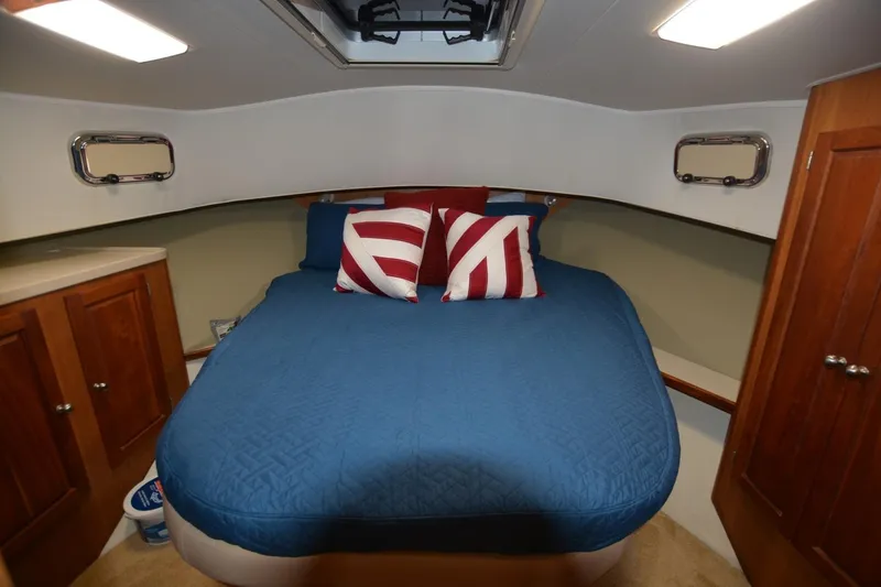 Slide: The Image of Cozy cabin interior of 2004 Mainship 400 Trawler with blue bedding and nautical decor. - 17