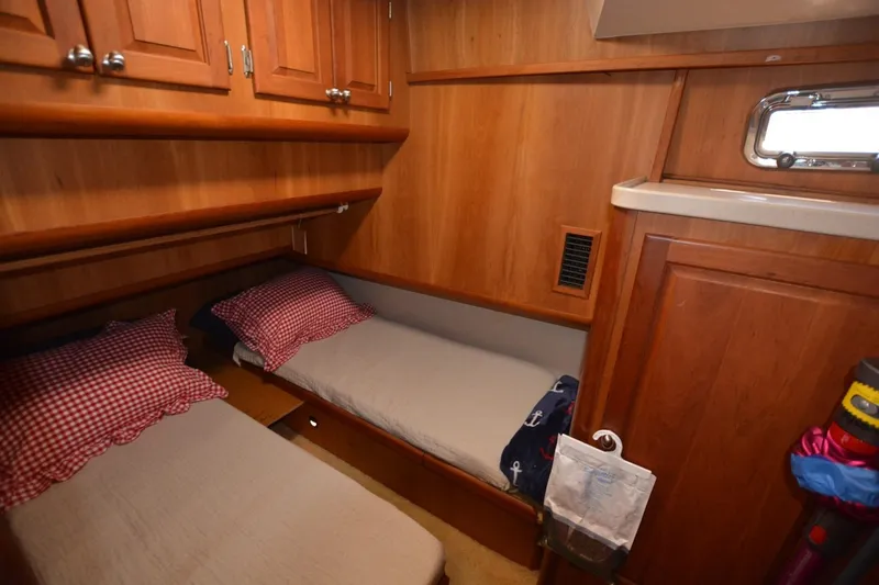 Slide: The Image of 2004 Mainship 400 Trawler cabin with twin beds, wooden cabinetry, and a small window. - 19