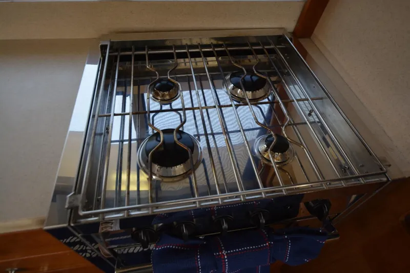 Slide: The Image of Stove in 2004 Mainship 400 Trawler kitchen, featuring four burners and metal grates. - 21