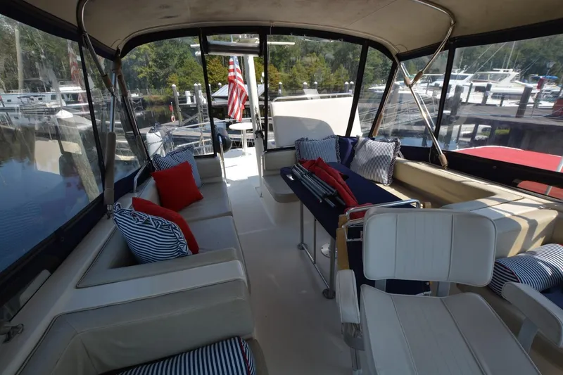 Slide: The Image of 2004 Mainship 400 Trawler interior with seating, cushions, and marina view. - 6