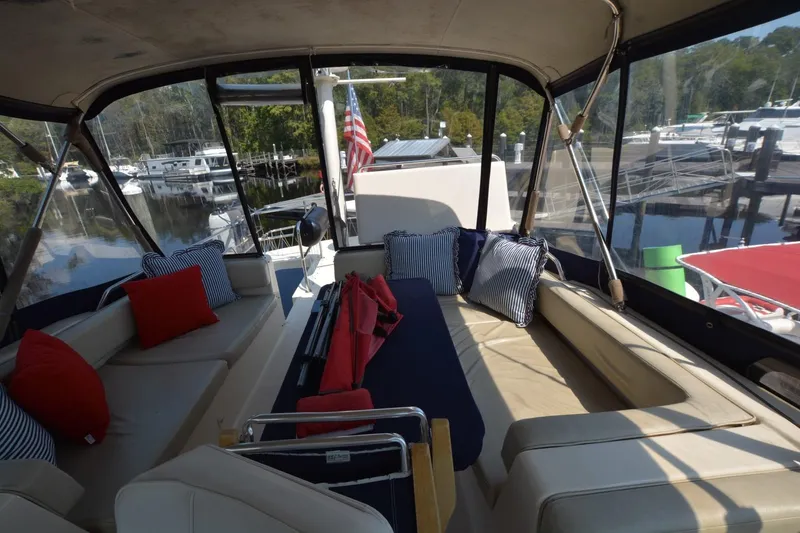 Slide: The Image of 2004 Mainship 400 Trawler interior with cushioned seating and marina view. - 7