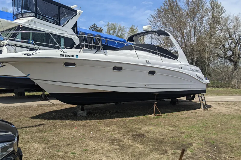Slide: The Image of 2002 Four Winns 328 Vista boat on dry land, supported by stands, under a clear sky. - 0