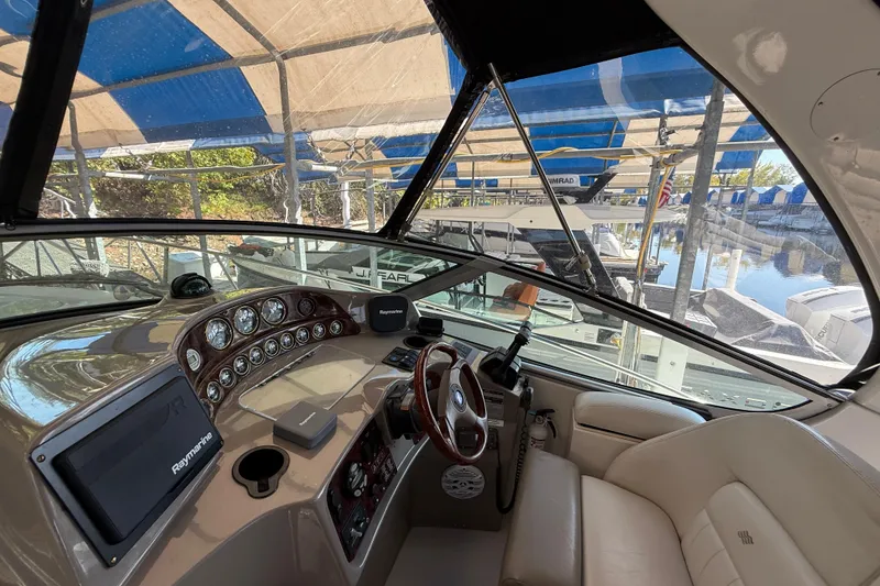 Slide: The Image of 2002 Four Winns 328 Vista boat cockpit with steering wheel, gauges, and Raymarine navigation system. - 24