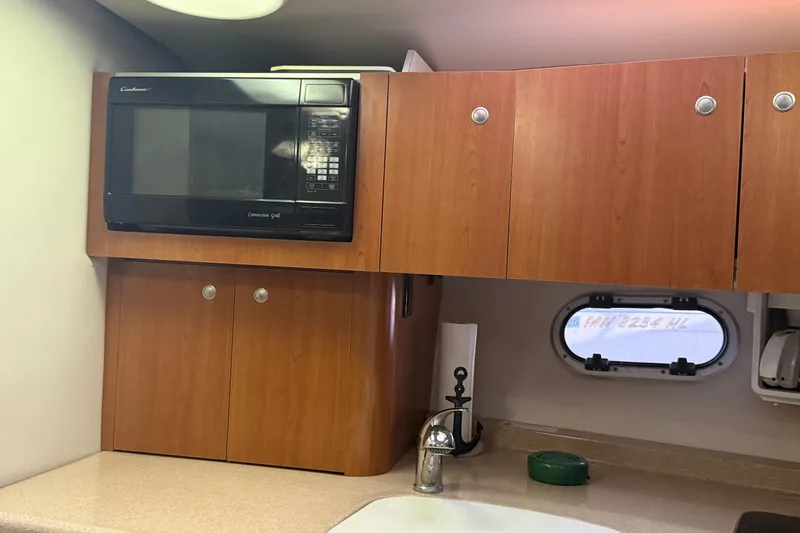 Slide: The Image of 2002 Four Winns 328 Vista kitchen with microwave, wooden cabinets, and porthole window. - 42