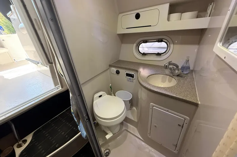 Slide: The Image of 2002 Four Winns 328 Vista boat bathroom with sink, toilet, and porthole window. - 48