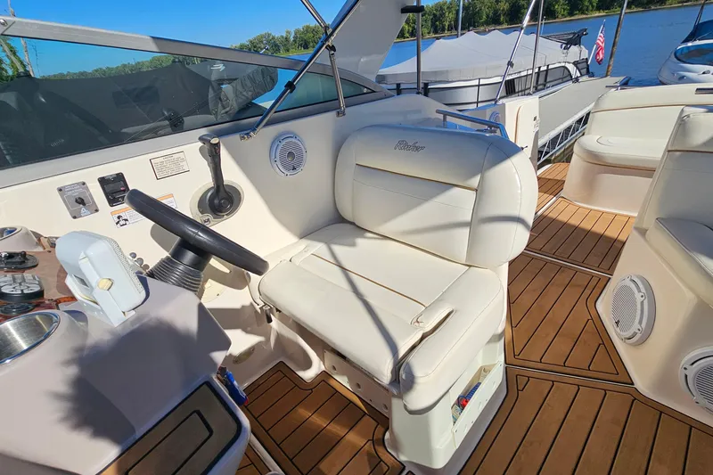 Slide: The Image of 2004 Rinker 270 Fiesta Vee boat cockpit with steering wheel and seating, docked by the water. - 10