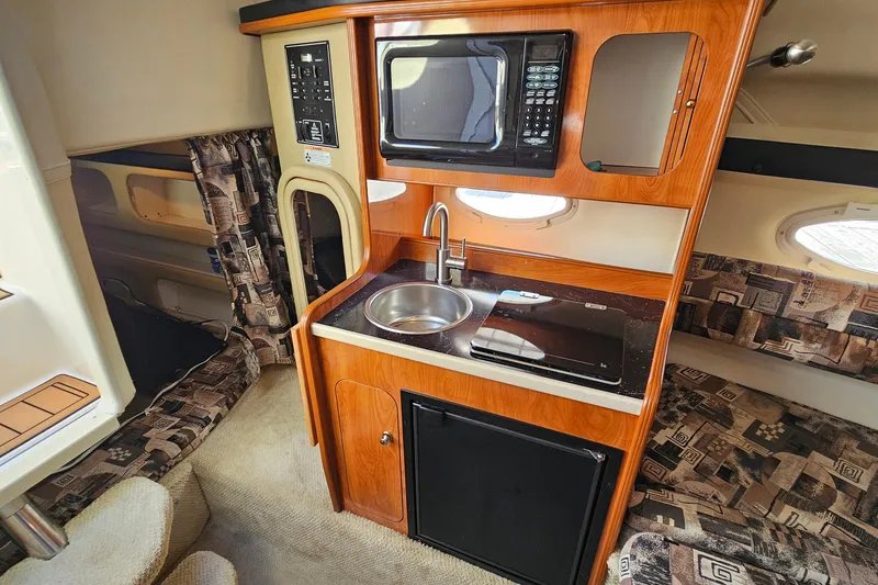 Slide: The Image of 2004 Rinker 270 Fiesta Vee cabin interior with kitchenette, microwave, and seating area. - 20