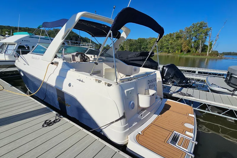 Slide: The Image of 2004 Rinker 270 Fiesta Vee boat docked on a sunny day, featuring a spacious deck. - 4