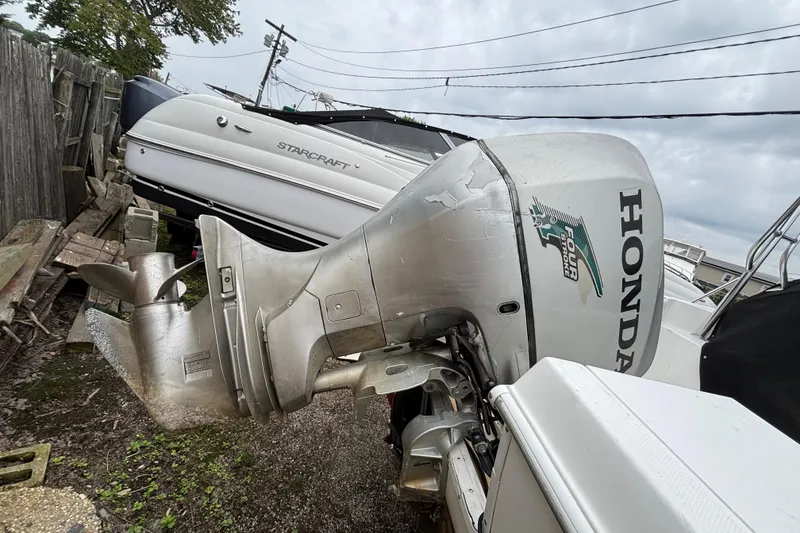 Slide: The Image of 1999 Wellcraft 22 Coastal Walkaround with Honda outboard motor, parked near a Starcraft boat. - 4