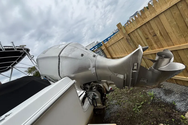 Slide: The Image of 1999 Wellcraft 22 Coastal Walkaround O/B boat with outboard motor, parked near wooden fence. - 5