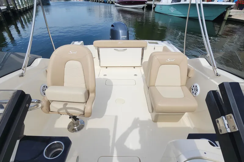 Slide: The Image of 2022 Scout 215 Dorado boat interior with beige seating and water backdrop. - 9