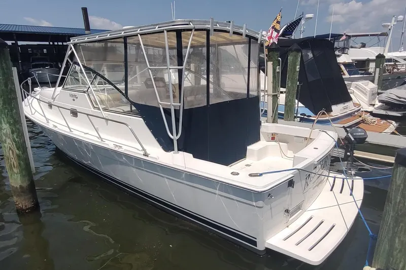 Slide: The Image of 2003 Mainship 34 PILOT boat docked at marina, featuring enclosed cockpit and sleek design. - 1