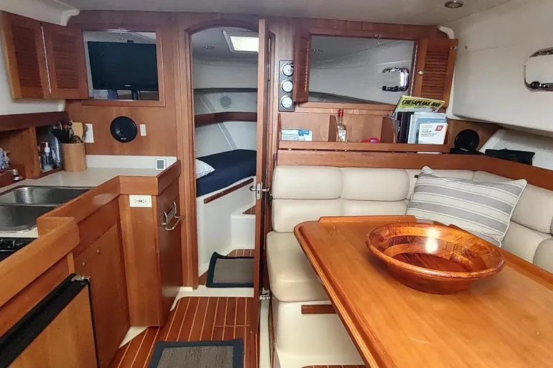 Slide: The Image of 2003 Mainship 34 Pilot interior with wood finishes, kitchenette, and cozy seating area. - 11