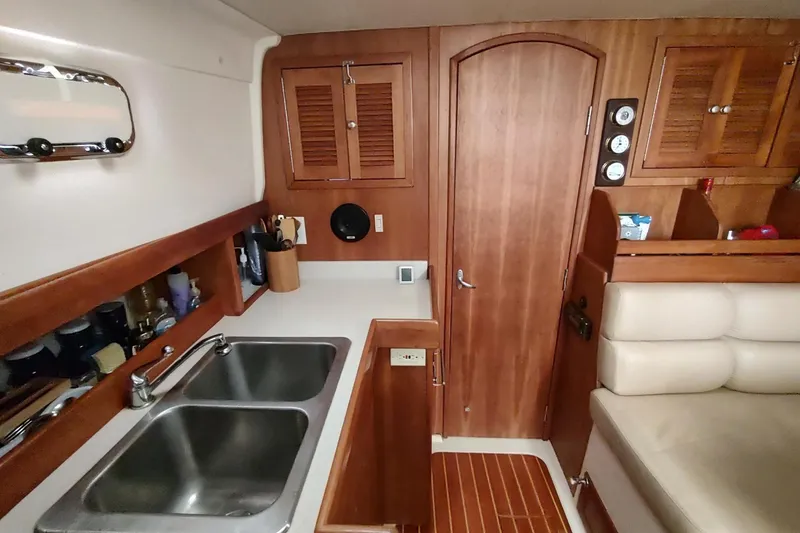 Slide: The Image of 2003 Mainship 34 PILOT interior with wooden cabinetry, dual sinks, and cozy seating area. - 12