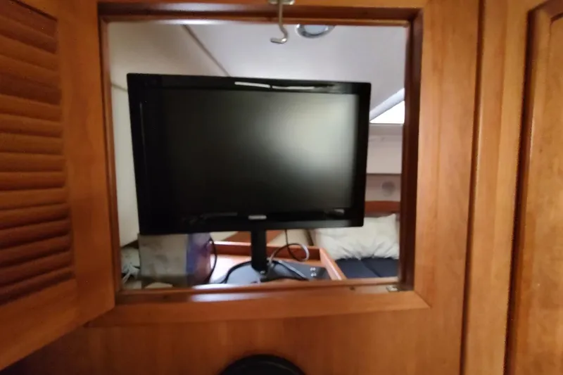 Slide: The Image of 2003 Mainship 34 PILOT interior with mounted TV and wooden cabinetry. - 14