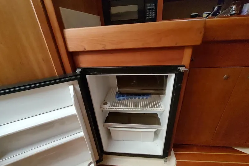 Slide: The Image of Open mini fridge in 2003 Mainship 34 PILOT boat galley, wooden cabinetry visible. - 16