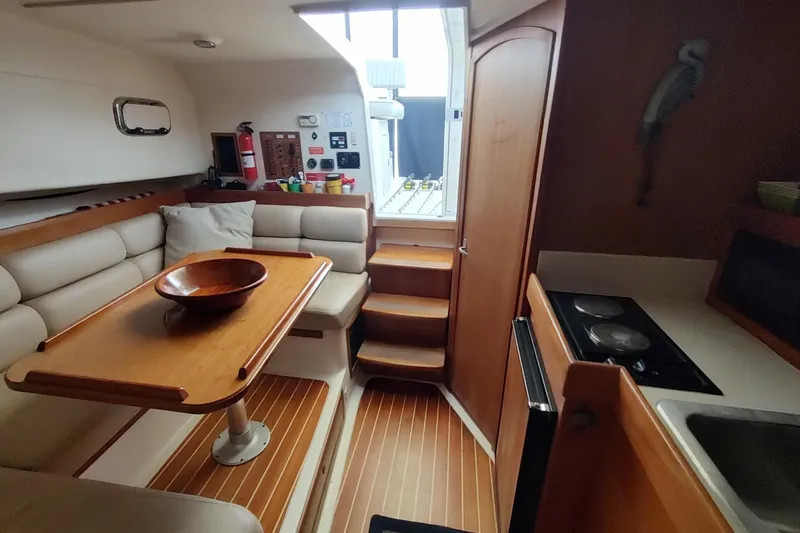 Slide: The Image of 2003 Mainship 34 Pilot interior with dining area, kitchenette, and wooden accents. - 27