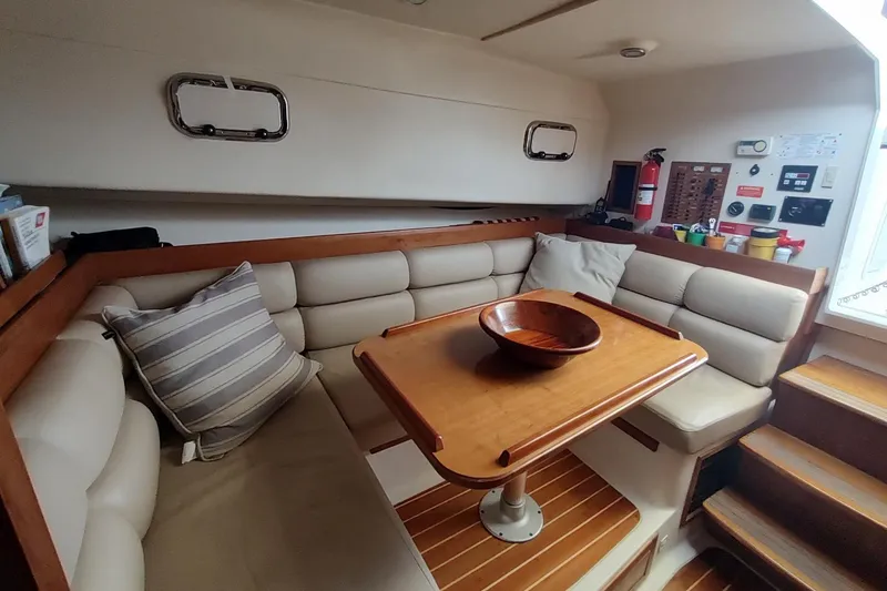 Slide: The Image of Cozy interior of 2003 Mainship 34 PILOT with cushioned seating and wooden table. - 28