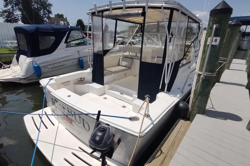 Slide: The Image of 2003 Mainship 34 PILOT docked, featuring a covered cockpit and adjacent boat. - 3