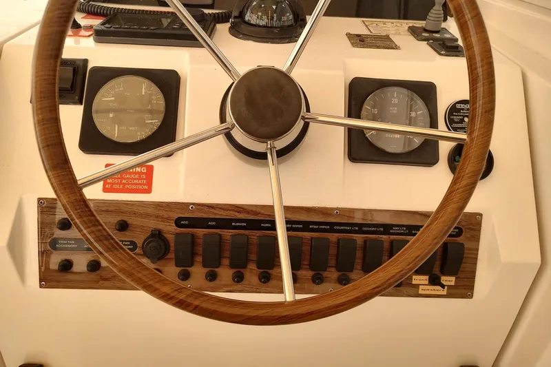 Slide: The Image of Steering wheel and dashboard of 2003 Mainship 34 PILOT boat, featuring gauges and controls. - 40