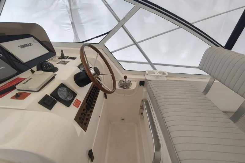 Slide: The Image of 2003 Mainship 34 PILOT helm with steering wheel, navigation equipment, and cushioned seating. - 52