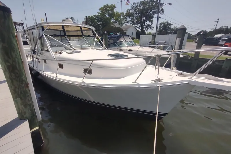 Slide: The Image of 2003 Mainship 34 PILOT boat docked at marina, featuring sleek white design and spacious deck. - 6