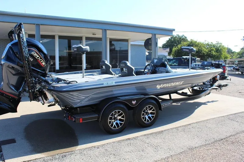 Slide: The Image of 2026 Phoenix 921 ELITE boat with trailer, parked outdoors, showcasing sleek design and modern features. - 2