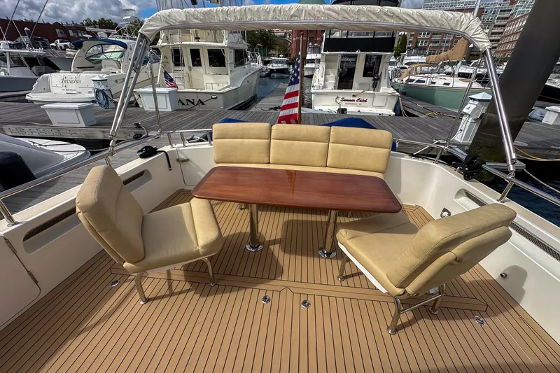 Slide: The Image of 2017 MJM 50z yacht deck with cushioned seating and wooden table at marina. - 6