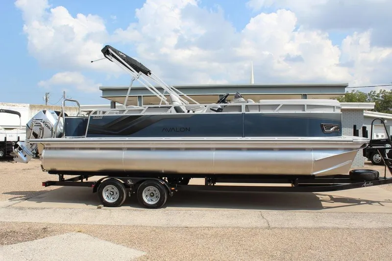 The Image of 2026 Avalon LSZ Cruiser Rear Bench 23 pontoon boat on trailer, parked outdoors. - 1