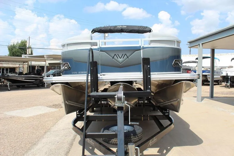 Slide: The Image of 2026 Avalon LSZ Cruiser Rear Bench 23 pontoon boat on trailer, displayed outdoors. - 6