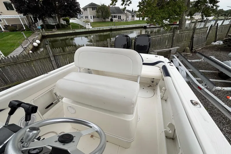 Slide: The Image of 1999 Wellcraft 302 Scarab Sport boat interior with steering wheel and seating, docked by a canal. - 8