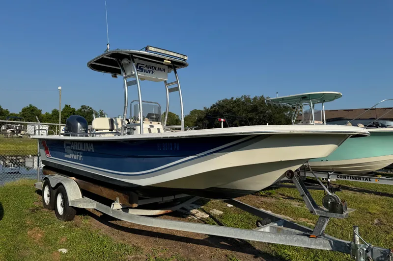 Slide: The Image of 2012 Carolina Skiff 238 DLV boat on trailer, parked outdoors under clear sky. - 2