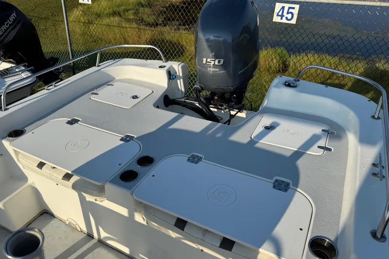 Slide: The Image of 2012 Carolina Skiff 238 DLV boat deck with Yamaha 150 engine, docked near fence. - 30