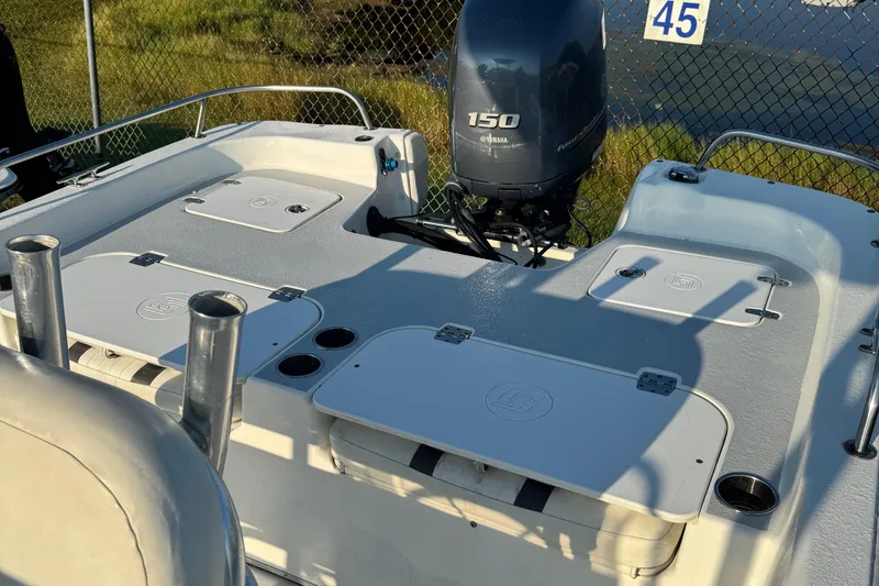 Slide: The Image of 2012 Carolina Skiff 238 DLV boat with Yamaha 150 engine, docked near a chain-link fence. - 37