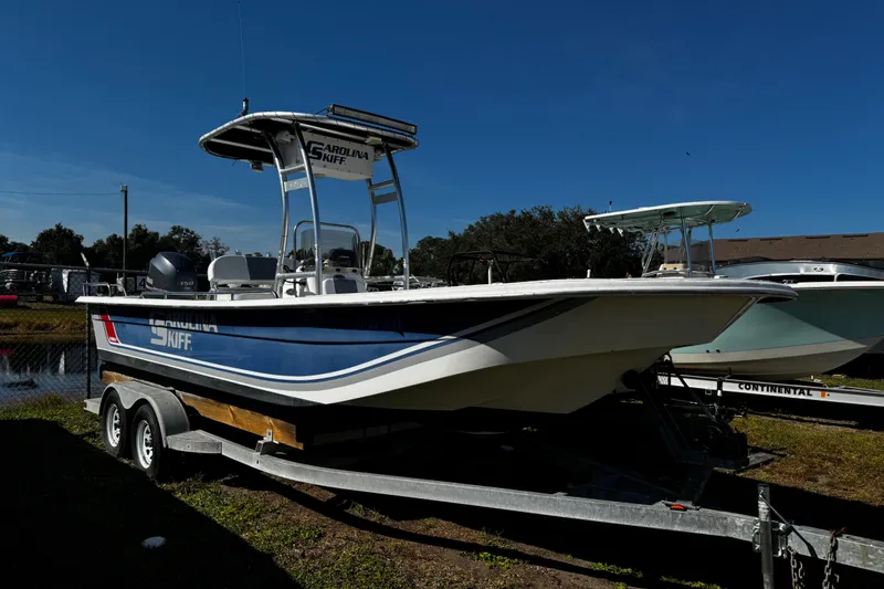 Slide: The Image of 2012 Carolina Skiff 238 DLV boat on trailer, parked outdoors under clear blue sky. - 45