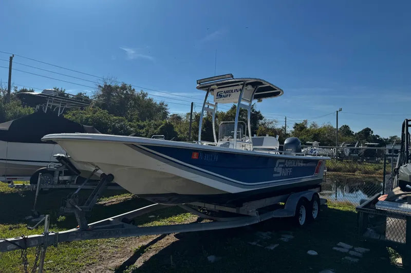 Slide: The Image of 2012 Carolina Skiff 238 DLV boat on trailer, parked outdoors under clear sky. - 46