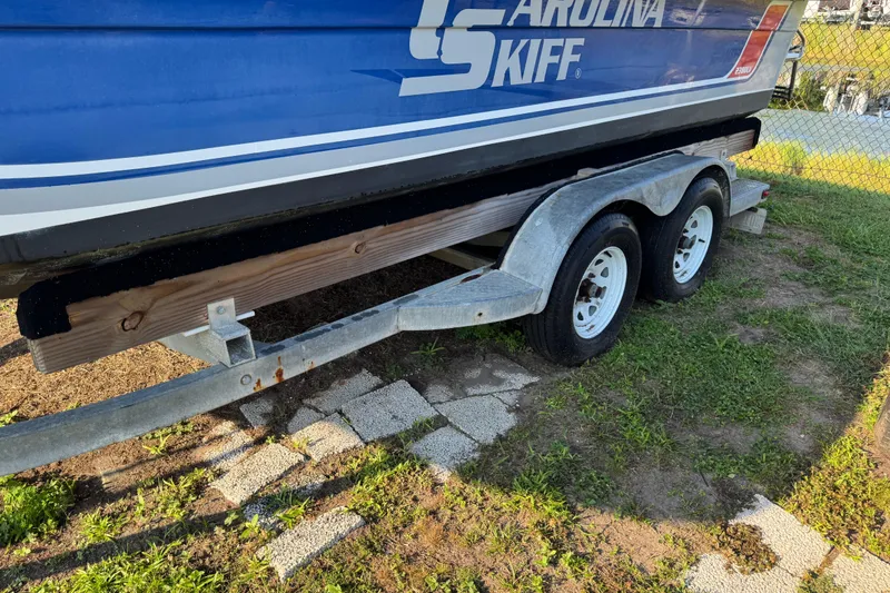 Slide: The Image of 2012 Carolina Skiff 238 DLV boat on trailer, parked on grass near a fence. - 6