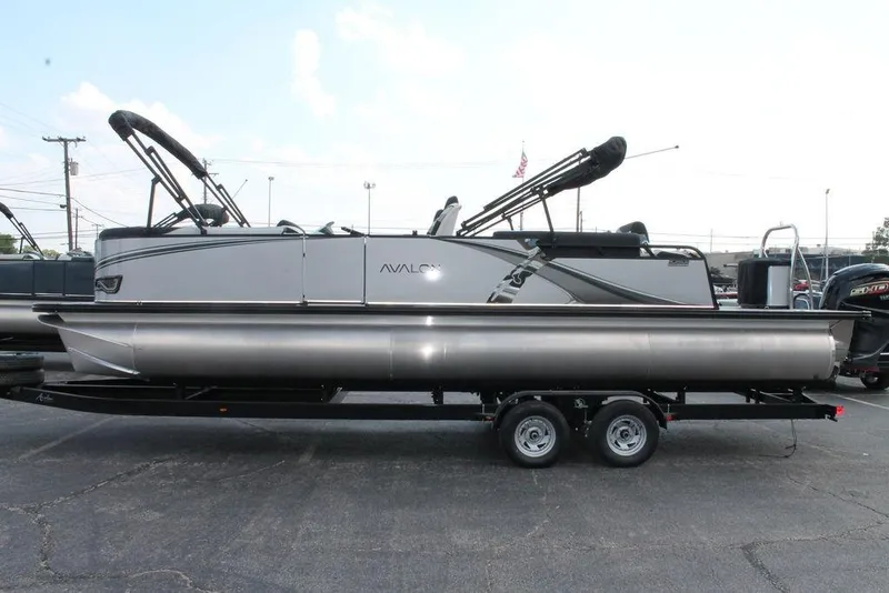 Slide: The Image of 2026 Avalon LSZ Quad Lounger Shift pontoon boat on trailer, side view. - 2