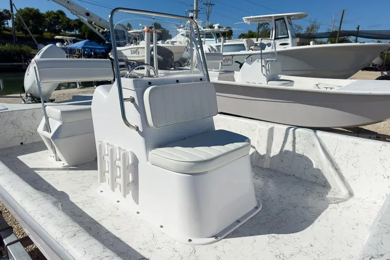Slide: The Image of 2026 Coastal Skiff 171 boat with white seating and console, docked in a marina. - 10