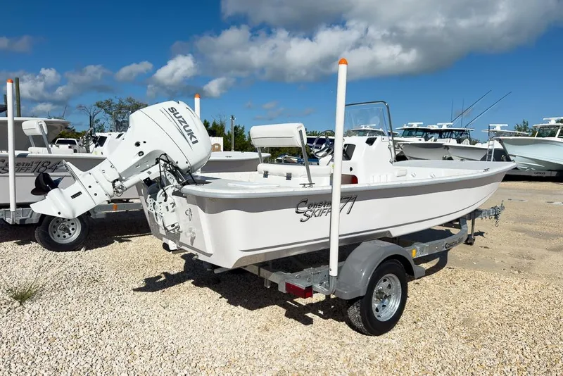 Slide: The Image of 2026 Coastal Skiff 171 boat on trailer with Suzuki outboard motor, parked on gravel. - 3
