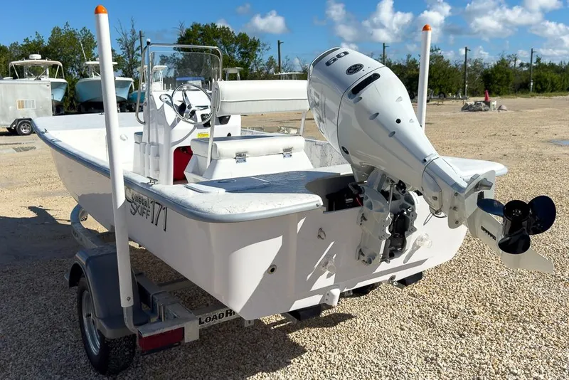 Slide: The Image of 2026 Coastal Skiff 171 boat on trailer with outboard motor, parked on gravel. - 5