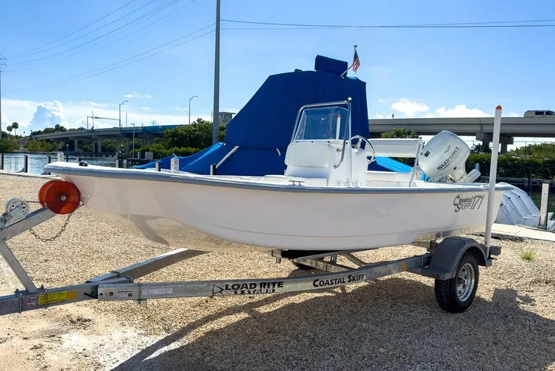 Slide: The Image of 2026 Coastal Skiff 171 boat on trailer by waterfront, sunny day. - 6