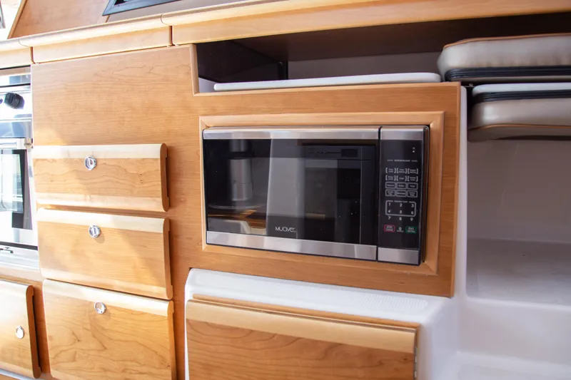 Slide: The Image of 2025 Cutwater C-32 Coupe interior with built-in microwave and wooden cabinetry. - 9