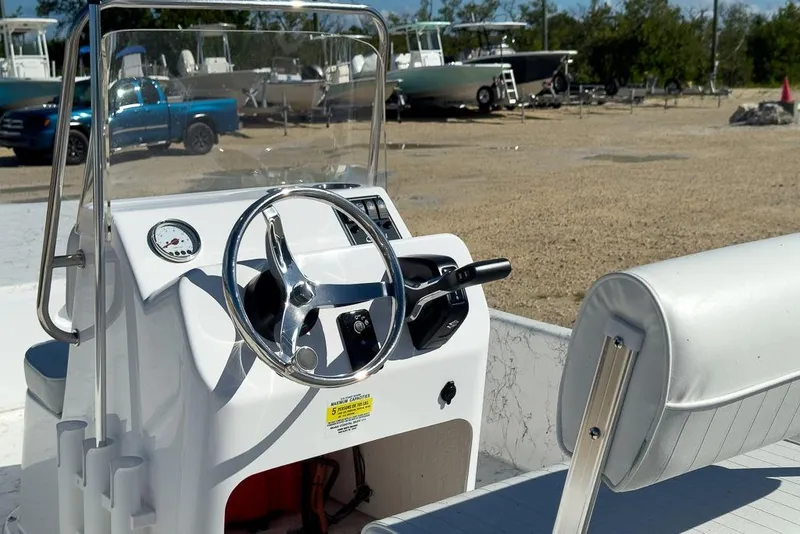 Slide: The Image of 2026 Coastal Skiff 171 boat console with steering wheel and gauge, parked outdoors. - 9