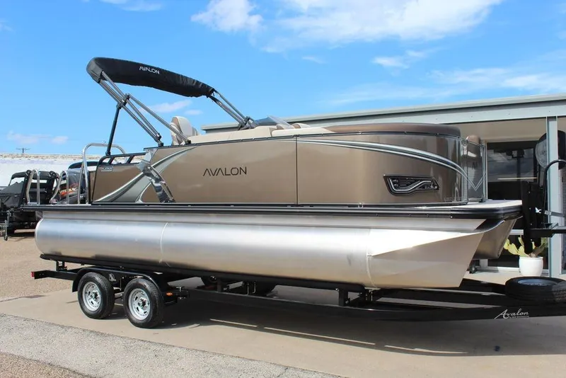 The Image of 2026 Avalon LSZ Cruise Rear Bench 21 pontoon boat on trailer, under clear blue sky. - 1
