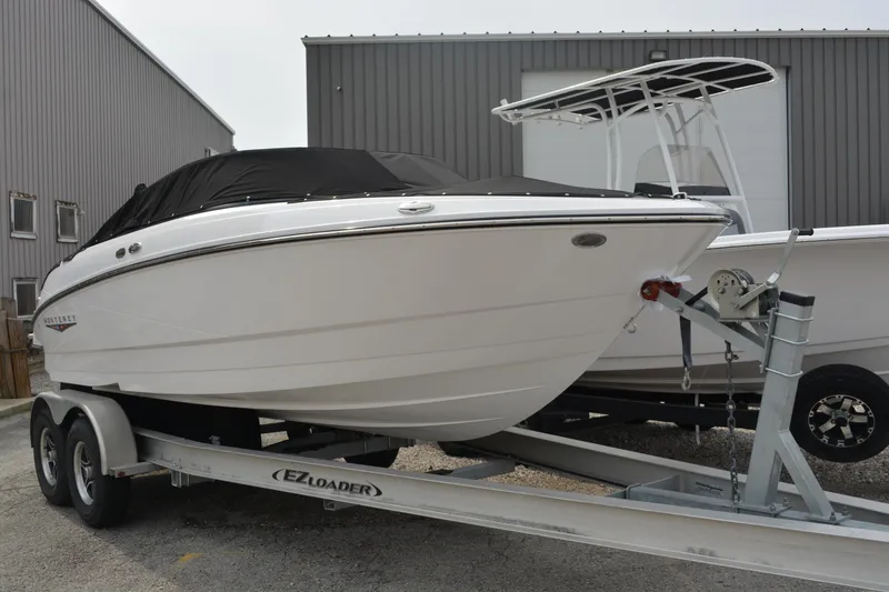 The Image of 2026 Monterey M-20 boat on trailer, covered and parked near a warehouse. - 0