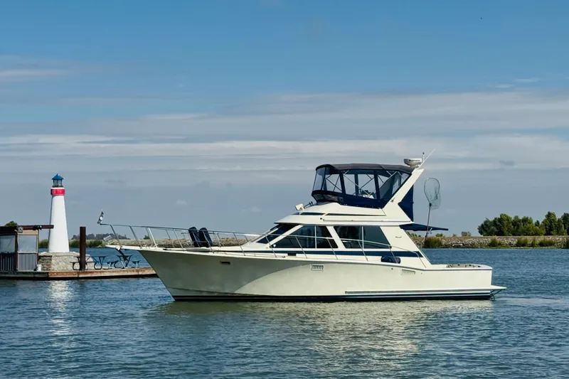 Slide: The Image of 1987 Tollycraft 40 Sport Sedan yacht near a lighthouse on calm water. - 6