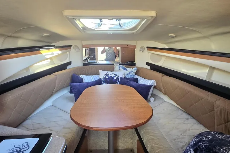 Slide: The Image of Interior of 2006 Sea Ray 260 Sundancer with cozy seating and wooden table. - 10