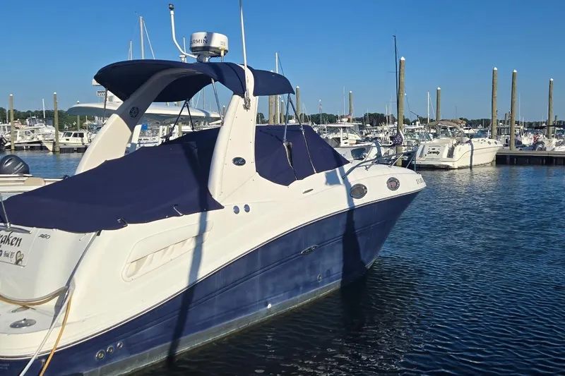 Slide: The Image of 2006 Sea Ray 260 Sundancer docked at marina, blue and white design, clear sky. - 2