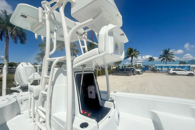 Slide: The Image of 2026 Yellowfin 24 Bay CE boat with T-top, parked near palm trees under blue sky. - 6